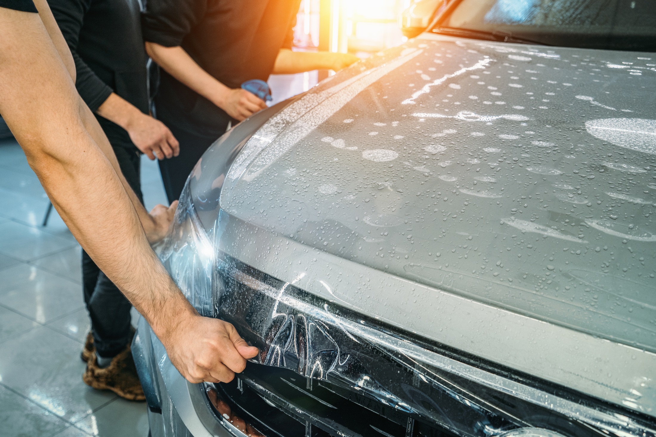 Clear paint protection film being installed on a vehicle front end